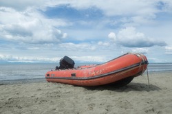 Red inflatable or rigid hulled boat on a alaskan beach 