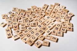 Alphabet letters on wooden scrabble pieces scattered randomly on white background