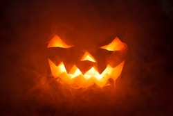 Scary Halloween Pumpkin looking through the smoke. Glowing, smoking monster pumpkin from depths of hell
