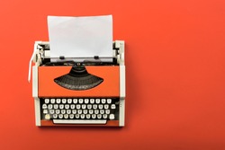 Top view of red vintage typewriter with white blank paper sheet on table