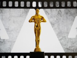 Hollywood Golden Oscar Academy award statue on old movie film background with copy space. Success and victory concept.