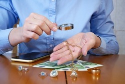 Pawnshop worker verify jewellery and photo or video camera and give money. Customers Buy and Sell Precious Metals, Jewels, Ancient Coins and Second Hand Electric Appliances. Closeup