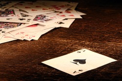 American West Legend vintage ace of spade playing card and stack of antique poker game cards on a weathered wood table in an old western frontier gambling establishment saloon