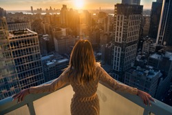 Rich woman enjoying the sunset standing on the balcony at luxury apartments in New York City. Luxury life concept. Successful businesswoman relaxing.