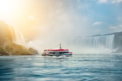 Niagara Falls boat tours attraction. Tourist people sailing on the travel boat close to the Niagara Horseshoe Fall at sunny hot summer day.