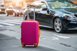 Luggage bag on the city street ready to pick by airport transfer taxi car.