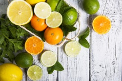 Citrus fruits in basket. Oranges, limes and lemons. Over white wood table background with copy space