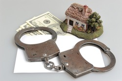 Handcuffs, toy house and white envelope with money on gray background
