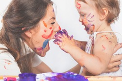 Happy mom and baby playing with painted face by paint. Mother day. Games with child affect early development. Important to spend enough time with your kids.