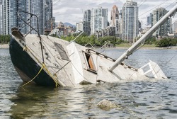 Sinking sailboat abandonned on the shore of a city

