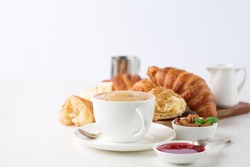 Fresh delicious breakfast with Coffee, crispy croissants, jam on white wooden background. Selective focus. Romantic french weekend concept. Copy space.