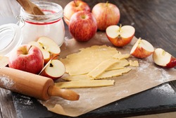 Baking apple pie ingredients - fresh apples, flour, eggs and sugar on rustic dark background, top view. Autumn concept