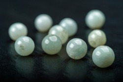 Collection of bluish green Jadeite spherical beads on dark background.
