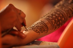 An artist making a beautiful henna or mehendi design on the hand of an Indian wife.