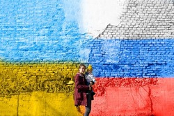 A woman with her child in front a wall painted in Ukrainian and Russian flag-truce concept