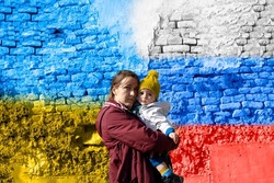 A woman holding her child in front of the Ukrainian and Russian flag-truce concept