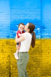Loving mother kissing her daughter in front of an old wall