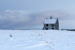Abandoned house sitting alone in a snowy field
