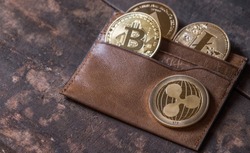 Popular cryptocurrency in leather wallet on wooden table top