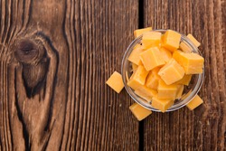 Pieces of Cheddar (detailed close-up shot) on rustic wooden background