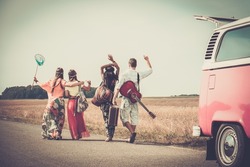 Multi-ethnic hippie friends with guitar and luggage 