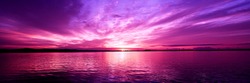 Delightful inspirational magenta coloured cloudy sea water tropical panoramic sunrise seascape featuring wispy cirrus clouds with sparkling ocean water reflections. Australia.