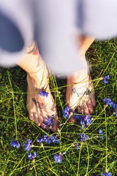 Woman in Blue Summer Dress with Tattooed Bare Feet Standing  on Grass and Cornflower Flowers.