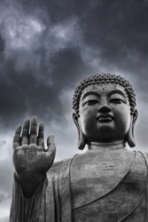 Blessing Buddha and moody sky with dark clouds in the  background