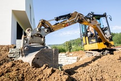 Mini excavator digging preparing ground under home garden