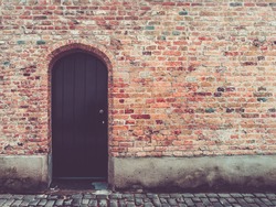 Old door in rustic brick wall, bruges, belgium