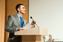 male speaker looks into the room and said into the microphone, speech at the conference