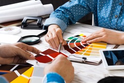 Cropped image of designer and client meeting in office. Creative workspace with color swatches and tablet computer. Interior and textile designing. Coloristics and product branding in design studio.