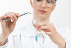 Young female research scientist puts bio sample into test tube. Biochemistry laboratory analysis and experimentation. Woman holding test tube and tweezers. Virology research and vaccine development.