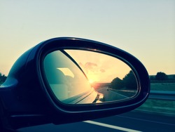 Sunset in a rear view mirror. Modern car on a highway.