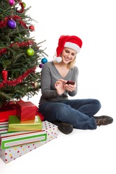 Happy woman wearing Santa hat shopping online for Christmas presents on a smart phone isolated on white