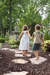 Two children walking down a garden path to a fountain