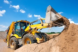 Wheel loader Excavator unloading sand with water during earth moving works at construction site