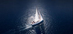 Sailing ship yachts with white sails at opened sea. Aerial - drone view to sailboat in windy condition.