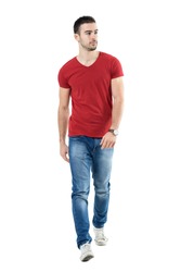 Young handsome casual man walk towards camera looking away. Full body length portrait isolated over white studio background.
