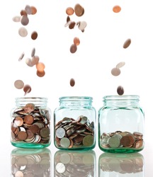 Savings rate concept - jars in row filling up with falling coins, focus on middle jar