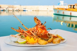 Lobster served with vegetables on white plate. Rethymno, Crete, Greece