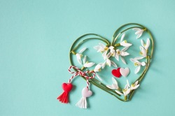 Green and turquoise background with a heart of snowdrops and red and white lace with tassels. Postcard for the holiday on March 1, Martisor, Baba Marta.