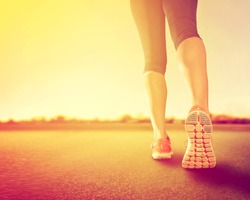  a woman with an athletic pair of legs going for a jog or run during sunrise or sunset - healthy lifestyle concept done with an instagram like filter 