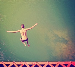  a boy jumping of an old train trestle bridge into a river done 
