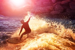 into the sun photo of a surfer riding a wave in a full wet suit toned with a retro vintage instagram filter app or action effect (SHALLOW DOF and long shutter speed action shot) 