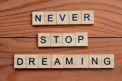 never stop dreaming text on wooden square, motivation quotes