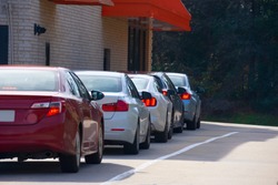 Generic drive thru pickup window with cars waiting in line to get their products or food.