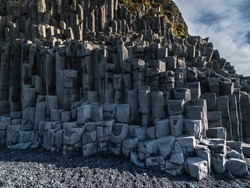 Basalt rock pillars columns at Reynisfjara beach near Vik, South Iceland. Unique geological volcanic formations. Natural stone texture background.