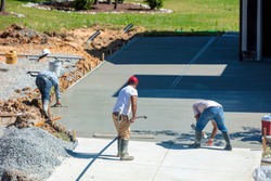 Unidentifiable hispanic men working on a new concrete driveway at a residential home
