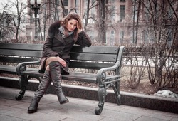 Sad girl sits on bench outdoors